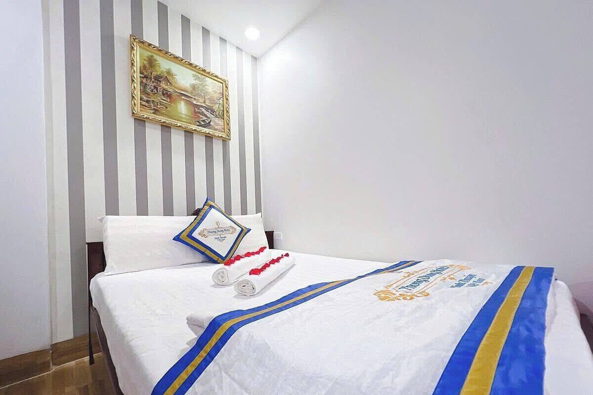 Een hotelkamer met een bed, streepjesbehang, een lijst met een foto en een decoratief kussen.