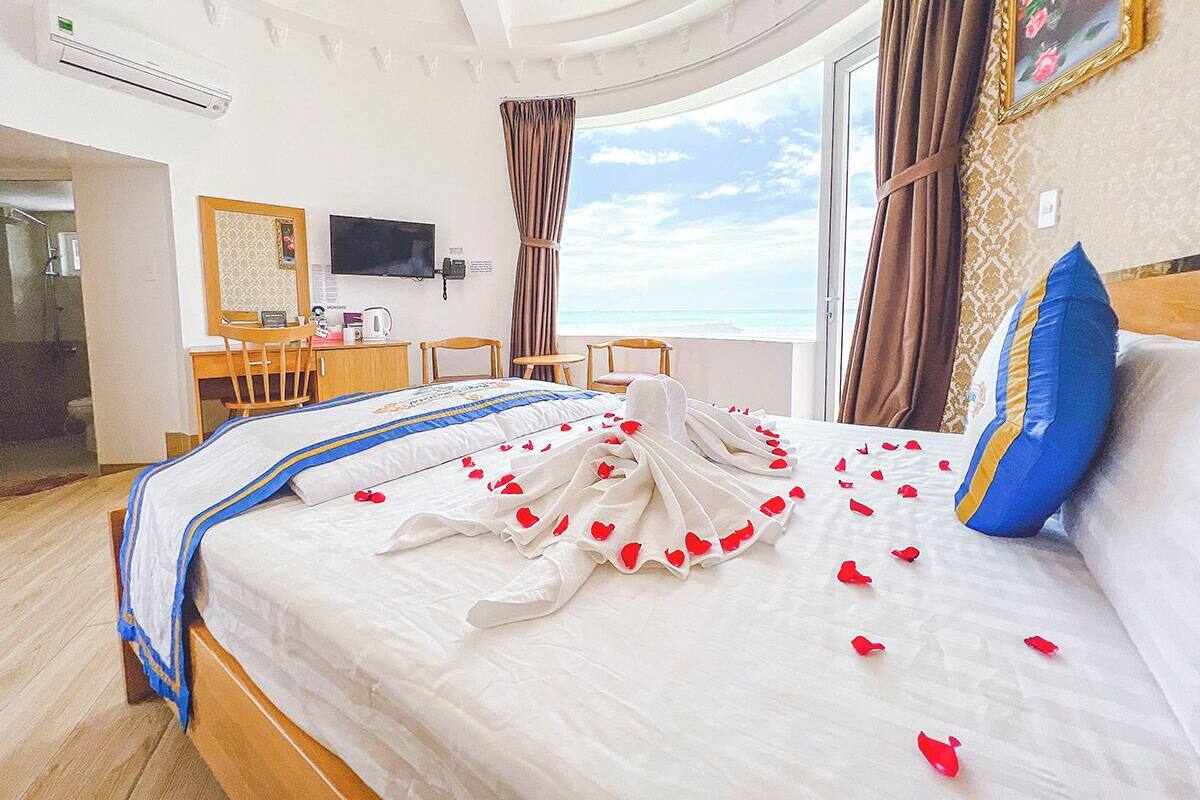 Een hotelkamer met een bed, een bureau, een stoel, een televisie en uitzicht op de lucht.