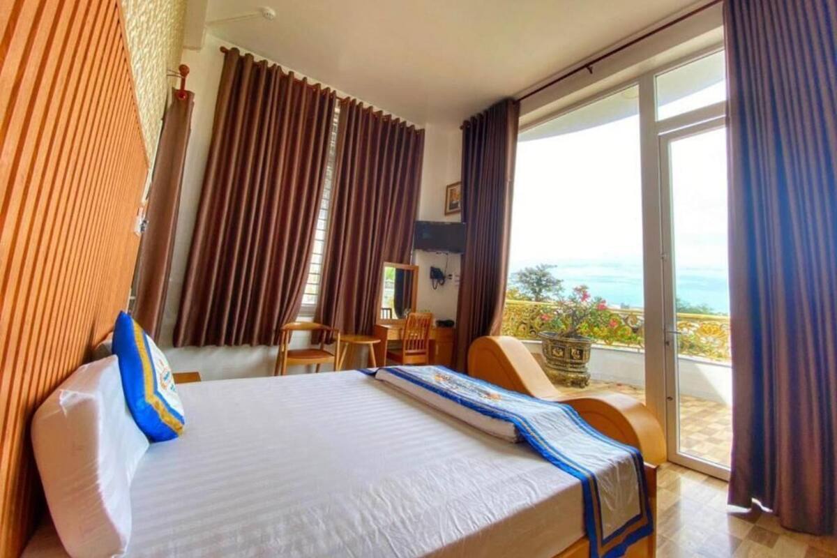 Een hotelkamer met een bed, een bureau, een stoel en een balkon met uitzicht.
