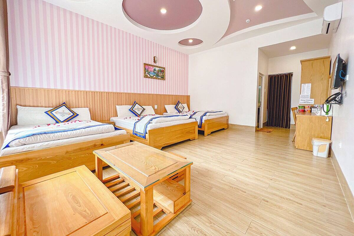 Een hotelkamer met drie bedden, houten meubels, een plafond met ronde lampen en een gestreept wand.