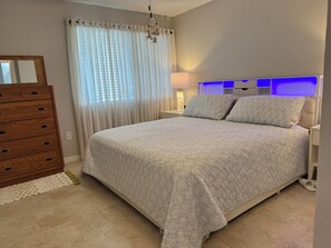 Un dormitorio con cama, cómoda, mesita de noche y lámpara.