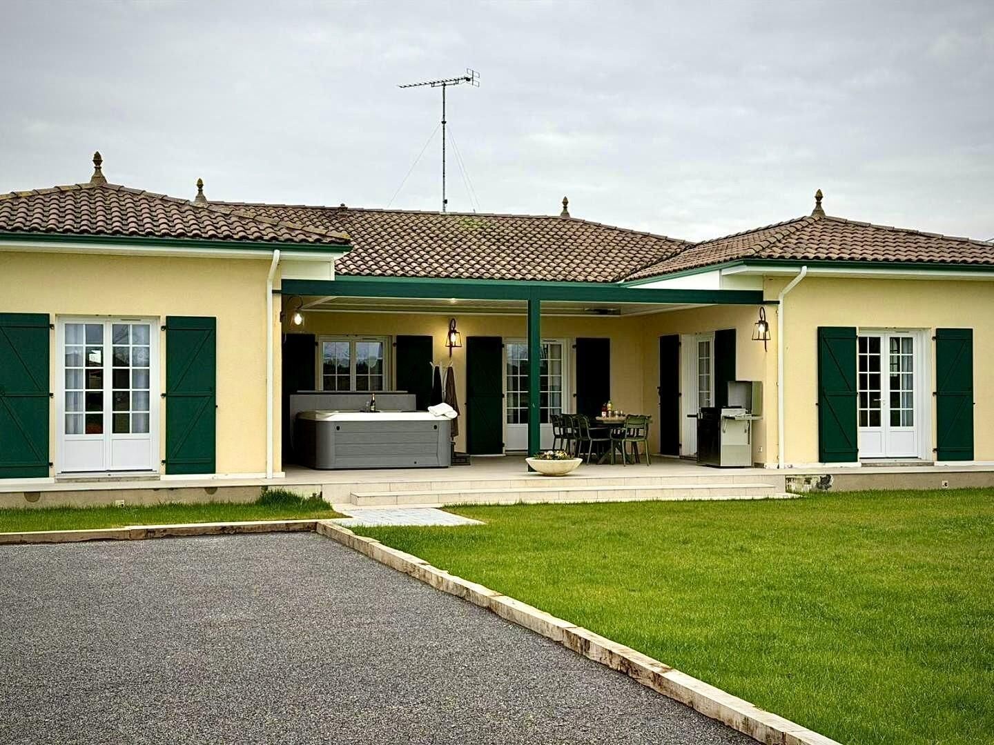 Ein zweistöckiges Haus mit überdachter Terrasse, Whirlpool und Satellitenschüssel.