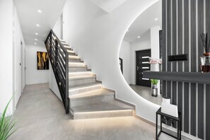 A modern interior with a curved staircase, a reception desk, and a minimalist design. - Villa Vella by Istrabook (Medulin)