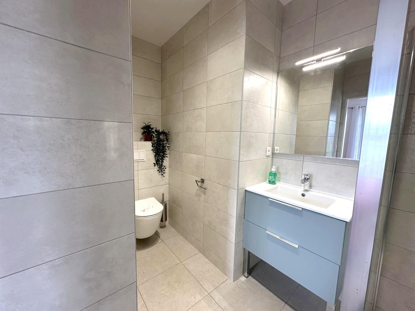 Une salle de bain avec des toilettes, un lavabo et un miroir.