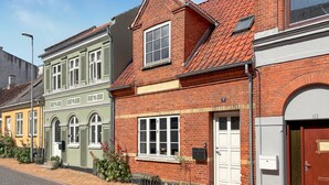 A row of colorful buildings with distinct architectural styles, including a red brick house with a white door and a green building with arched windows. - Lovely home in Rudkøbing with WiFi (Rudkøbing)