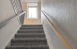 A staircase with a textured wall and a window at the top.