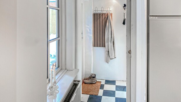 A hallway with a radiator, a pair of shoes on a mat, and a door with a striped curtain. - Lovely home in Rudkøbing with WiFi (Rudkøbing)