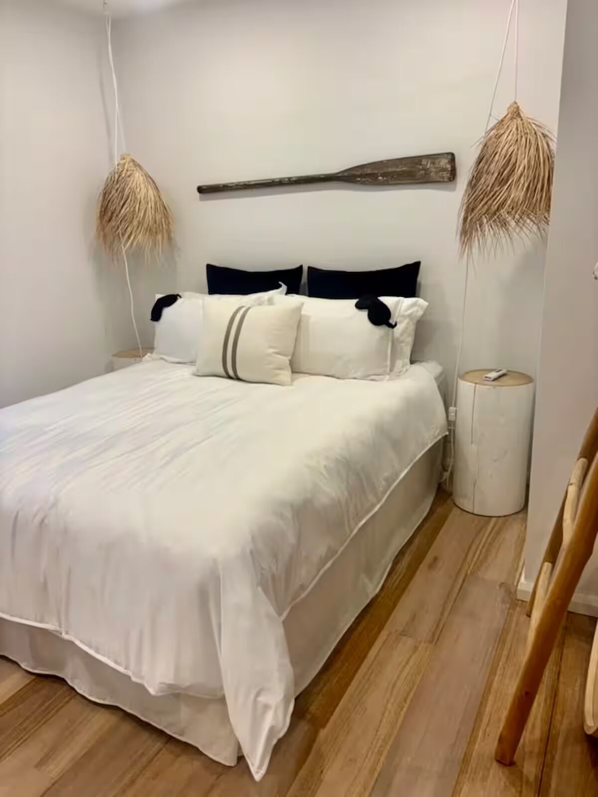 A bedroom with a bed, pillows, a bedside table, and a hanging light fixture.