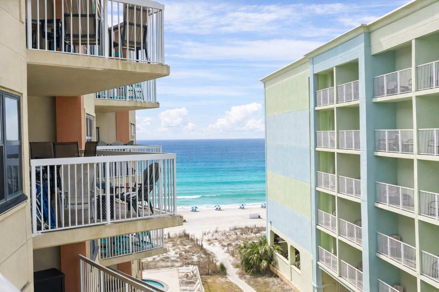 A multi-story hotel with balconies overlooking a beach.