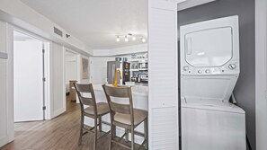 Eine moderne Küche mit weißen Schränken, einem Edelstahlkühlschrank sowie einer integrierten Waschmaschine und einem Trockner.