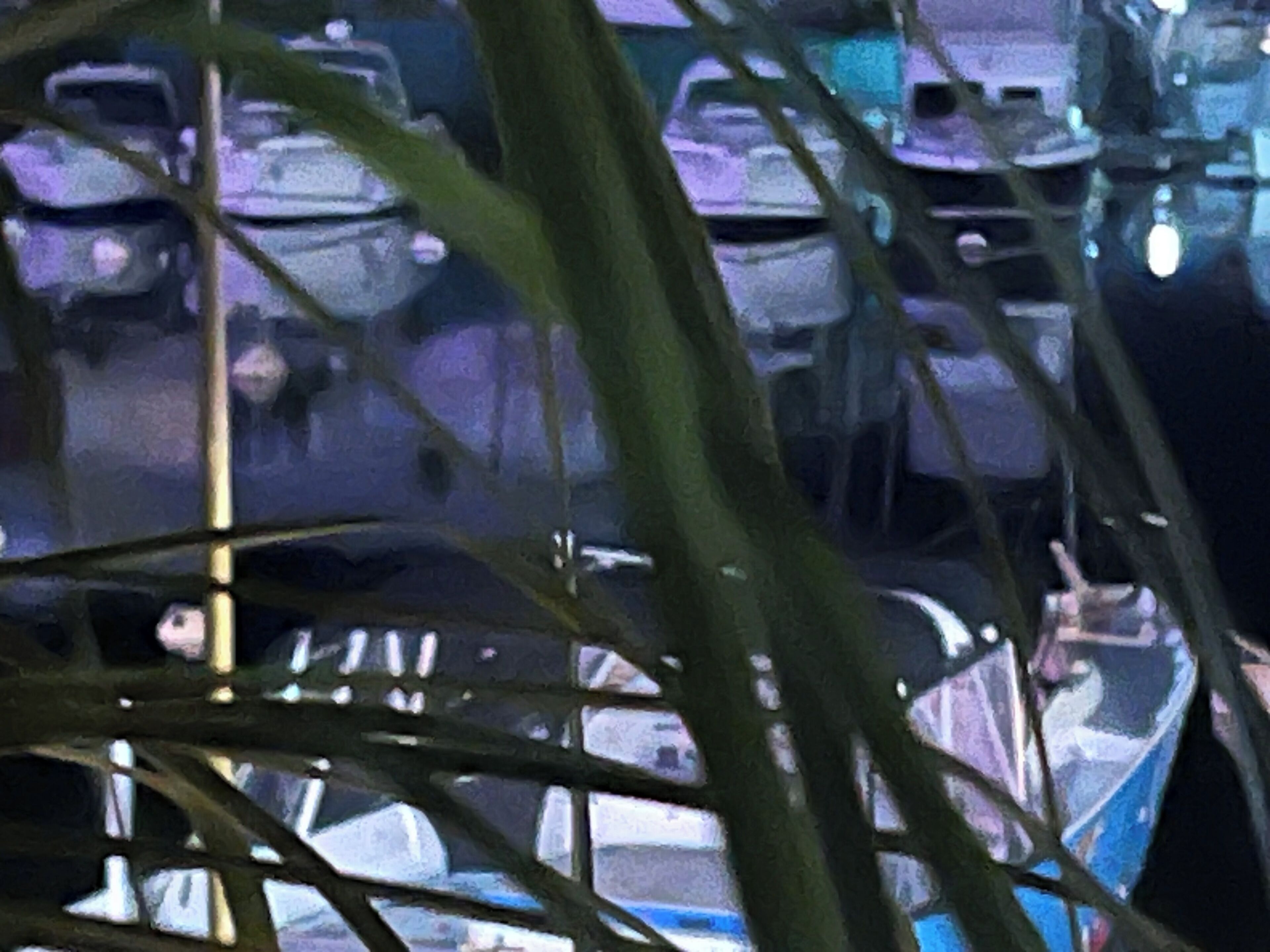 A view of a parking area with several cars and a few trees in the foreground.