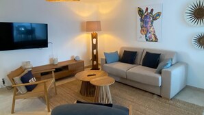 Uma sala de estar moderna com sofá, mesa de centro, televisão e luminária.