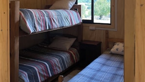 A wooden cabin room with two bunk beds, a window with a view of trees, and a ceiling fan. - Cabaña El Tilo - Getaway with a view of Ranco Lake (Riñinahue)