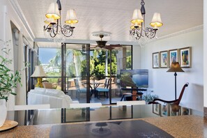 Una sala de estar moderna con un separador de vidrio, un ventilador de techo y un amplio ventanal con vistas al exterior.