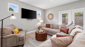A living room with a sofa, ottoman, and a flat-screen TV mounted on the wall. - 🦩Book Me Baby! Seascape at PCB🦩 (Panama City)