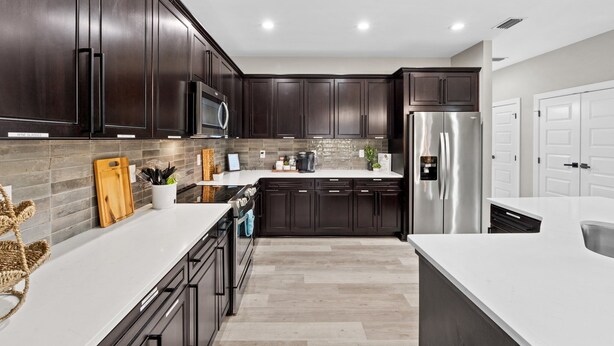 A modern kitchen with dark wood cabinets, stainless steel appliances, and a white countertop. - 🦩Book Me Baby! Seascape at PCB🦩 (Panama City)