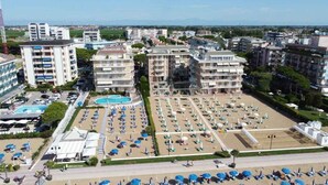 Een hotel met meerdere verdiepingen, een zwembad en een groot buitengebied met tal van parasols en ligbedden.