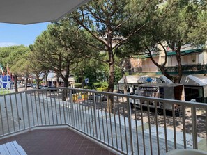Ein Balkon mit Blick auf eine von Bäumen und Gebäuden gesäumte Straße, darunter ein Restaurant namens "GASPAROTTO".
