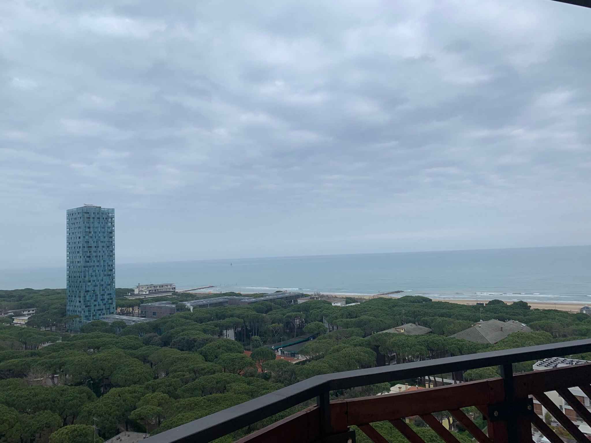 Ein Hochhaus mit Blick auf eine Küstenregion, einen Strand und dichtes Grün.