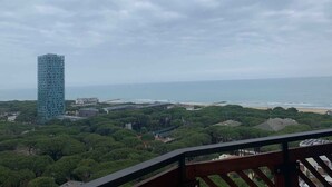 Un edificio alto con vistas a una zona costera, una playa y abundante vegetación.