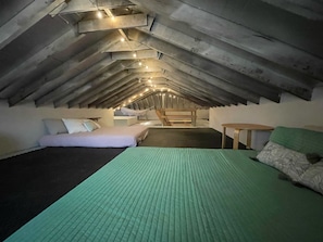 An attic bedroom with a sloped ceiling, a bunk bed, a small table, and string lights.