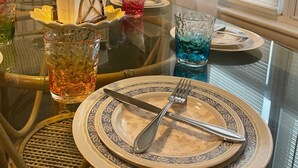 A dining table set with plates, cutlery, and glasses, with a chair in the foreground.
