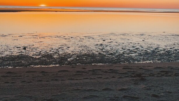 A beach with a calm sea and a clear sky.
