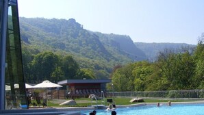 A swimming pool with people in it, surrounded by greenery and hills. - Hotel Restaurant Piccolo (Thale)