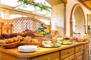 Una mesa de buffet con pan, frutas y ensaladas.