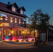 Un hotel con un letrero que dice 'Ristorante HOTEL', ventanas amplias y alumbrado exterior.