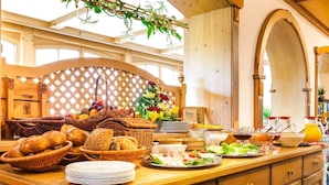 A buffet setup with various food items, including bread, salads, and condiments. - Hotel Restaurant Piccolo (Thale)