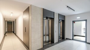 A modern hallway with two elevators, a door with a 'No Smoking' sign, and a clean, tiled floor. - Szybowcowa Charming Apartment (Katowice)