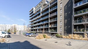 A modern multi-story residential building with balconies, a parking area, and a paved walkway. - Szybowcowa Charming Apartment (Katowice)