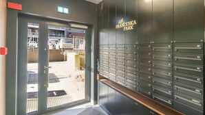 A building entrance with a metal door, a wall-mounted mailbox, and a row of numbered mailboxes. - Szybowcowa Charming Apartment (Katowice)