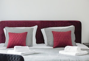 A neatly made bed with a red headboard, two pillows, and folded white towels. - Hanza Tower Studio 309 (Szczecin)
