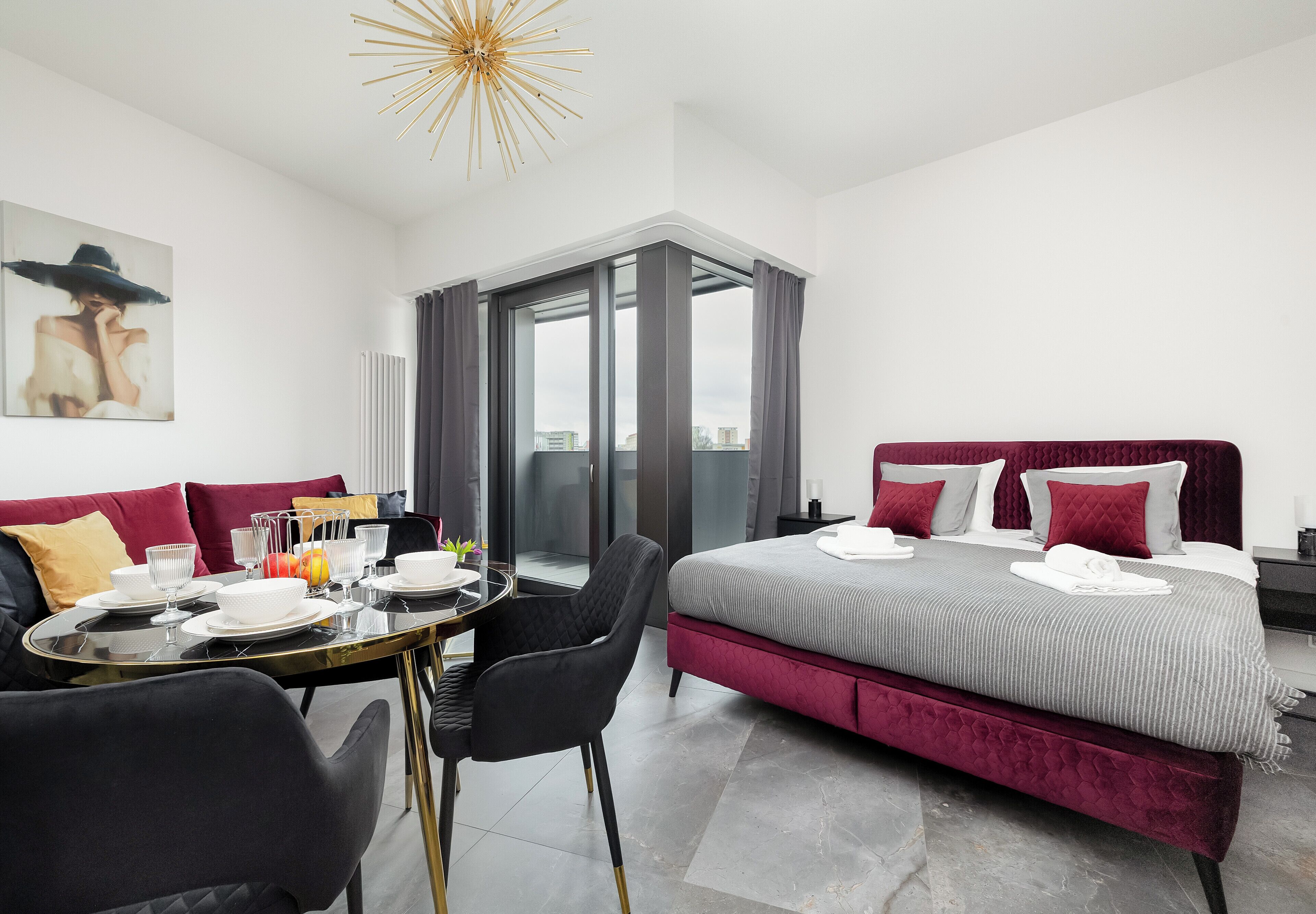 A modern hotel room with a bed, seating area, and a view through a glass door.