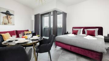 A modern hotel room with a bed, seating area, and a view through a glass door.