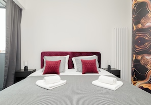 Ein ordentlich bezogenes Bett mit einer gestreiften Tagesdecke, zwei Kissen und zwei gefalteten Handtüchern.