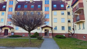 A multi-story residential building with a central entrance, a brick facade, and a small tree in the foreground. - Hłaski Urban Cozy Apartment (Wrocław)