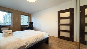 A bedroom with a bed, a desk, a chair, a window, and a door. - Hłaski Urban Cozy Apartment (Wrocław)