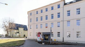 Un edificio de varios pisos con fachada plana, varias ventanas y una entrada pequeña.