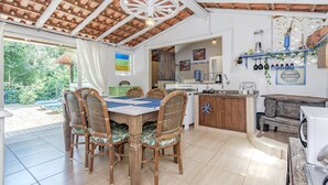 A kitchen with a dining area, featuring a large table, wicker chairs, a white ceiling fan, and a Heineken sign. - Casa em Condom nio com Piscina e rea Gourmet (Garopaba)