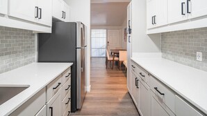 A modern kitchen with white cabinets, a black refrigerator, and a tiled backsplash. - Dwell Tranquil Stay with Pool and Gym (Scottsdale)