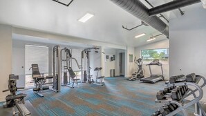 A gym with various exercise equipment, including treadmills, weight machines, and free weights. - Dwell Tranquil Stay with Pool and Gym (Scottsdale)