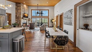 A spacious kitchen with a stone wall, wooden ceiling, and a large dining table with chairs. - Blue Ridge Retreat - Lakefront | Dock | Firepit | Game Room (Blue Ridge)