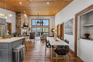 A spacious kitchen with a stone wall, wooden ceiling, and a large dining table with chairs. - Blue Ridge Retreat - Lakefront | Dock | Firepit | Game Room (Blue Ridge)