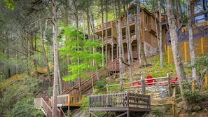 Eine mehrstöckige Holzhütte mit Holzausleger und Treppe, umgeben von Bäumen.