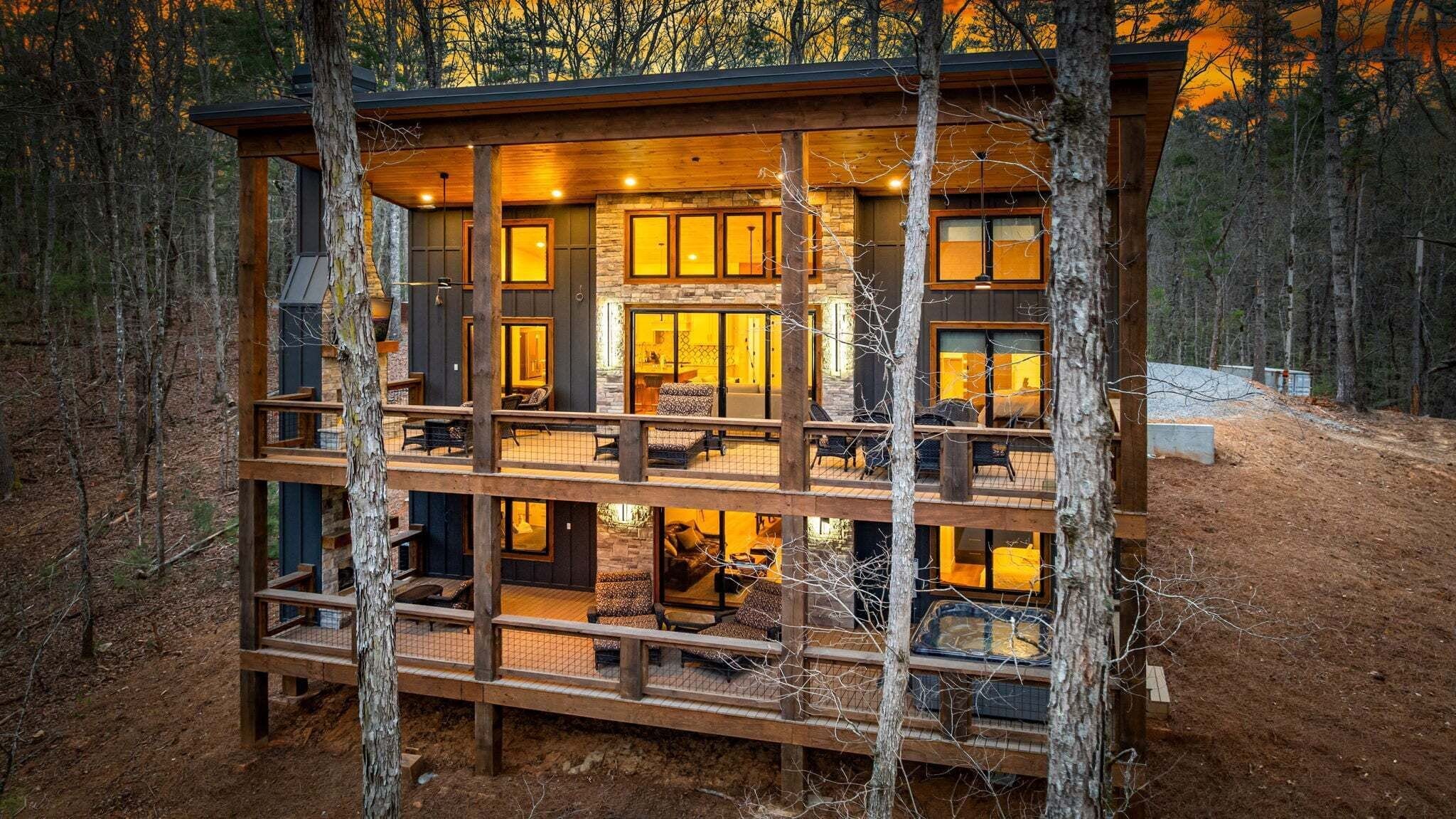 Una cabaña de varios niveles con revestimiento de madera, múltiples ventanas y un área de terraza.