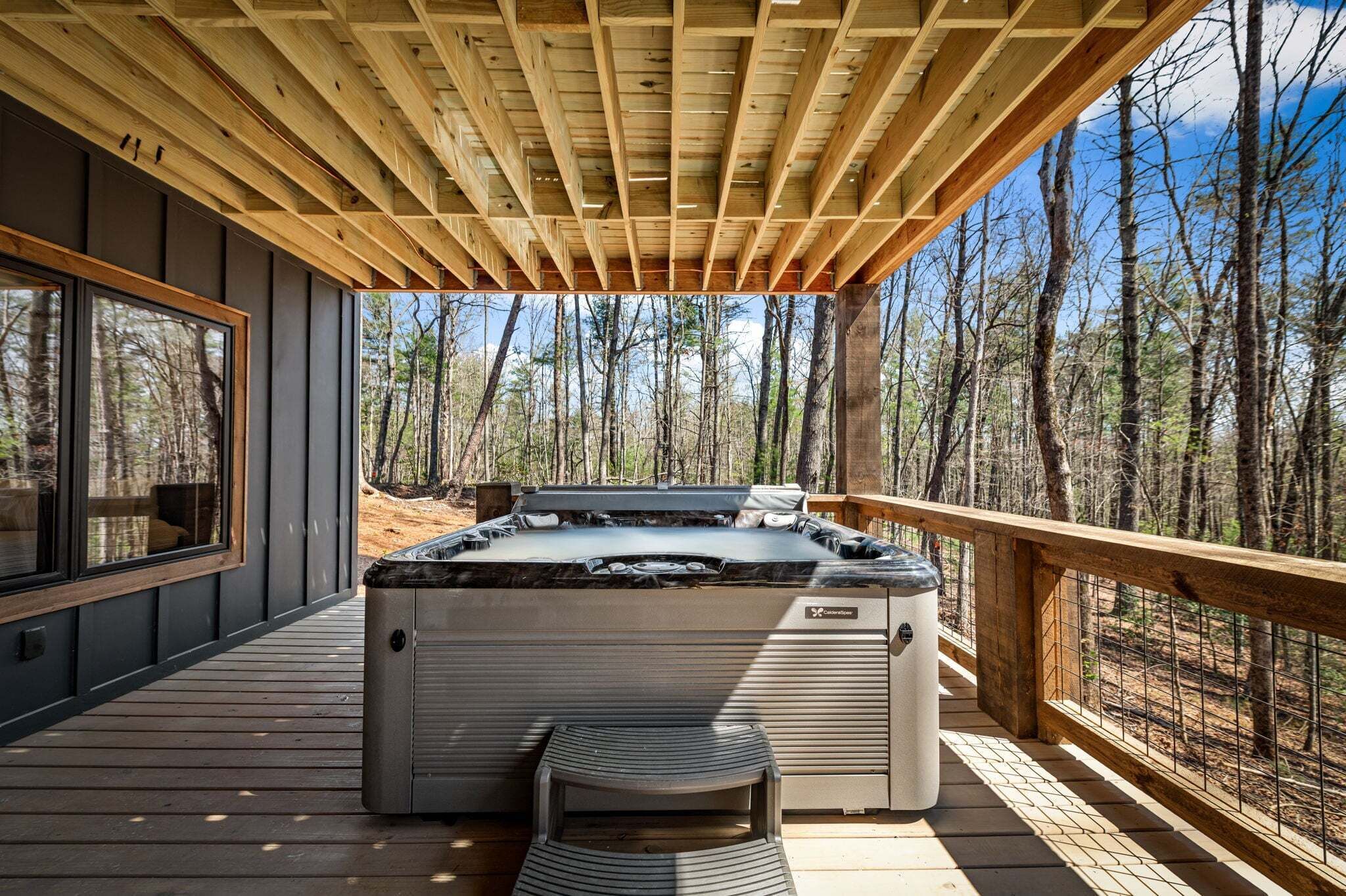 Ein Whirlpool auf einer Holzterrasse mit Blick auf einen Wald.