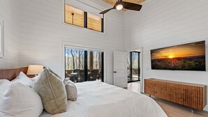 Camera da letto con un grande letto, una ventola a soffitto, una televisione e vista sull'esterno.